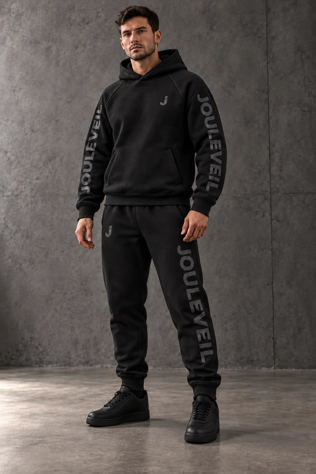 AI concept visualization of a model in a black JOULEVEIL hoodie and joggers with tonal sleeve and leg lettering.